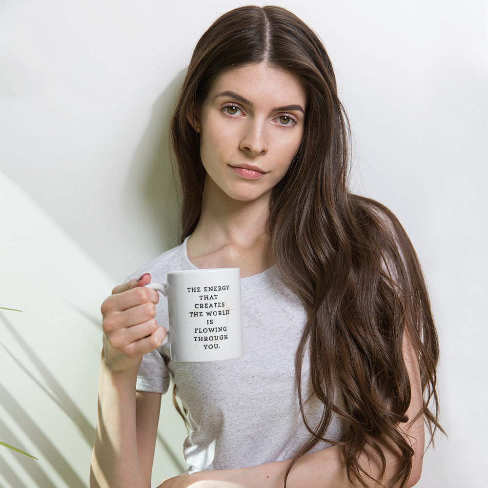 Liberty's Gaze, a girl with feathers in her hair, tied back in a pony tail, gazes towards the words on the other side of the mug which read, the energy that creates the world is flowing through you.