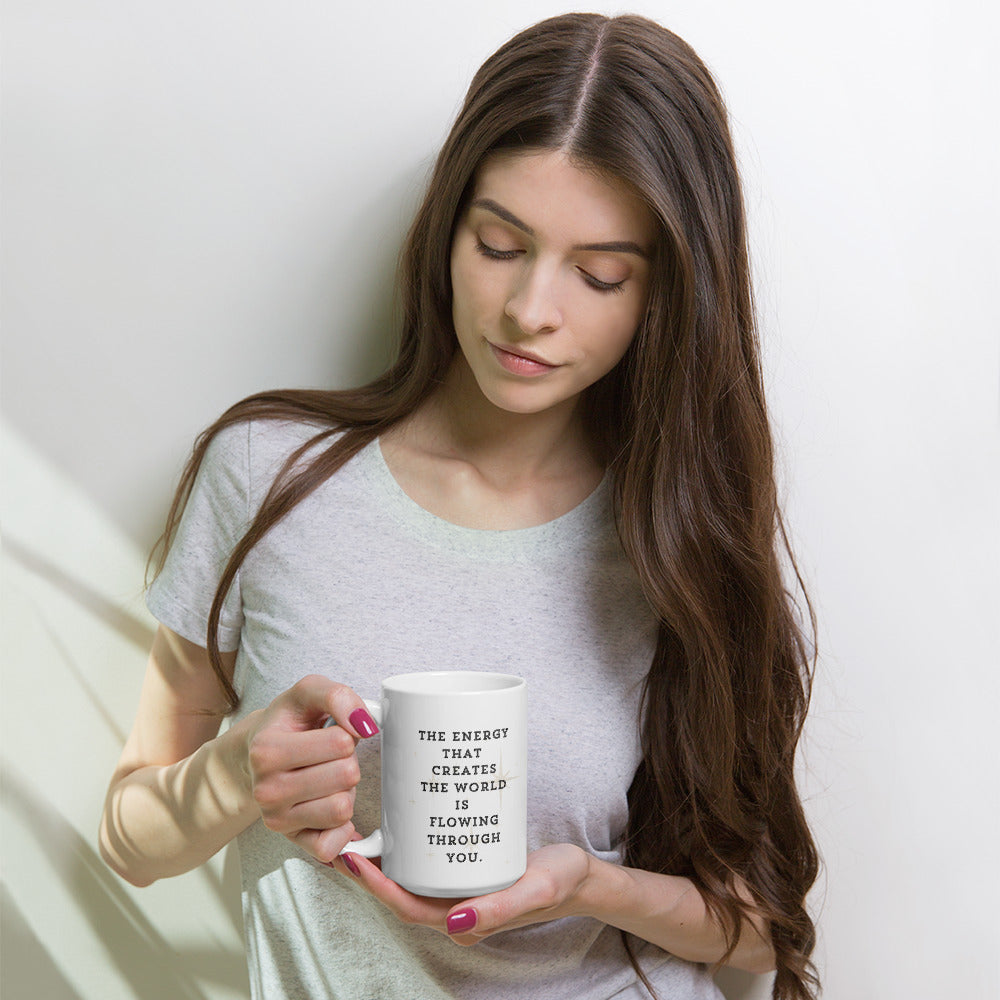 Liberty's Gaze, a girl with feathers in her hair, tied back in a pony tail, gazes towards the words on the other side of the mug which read, the energy that creates the world is flowing through you.